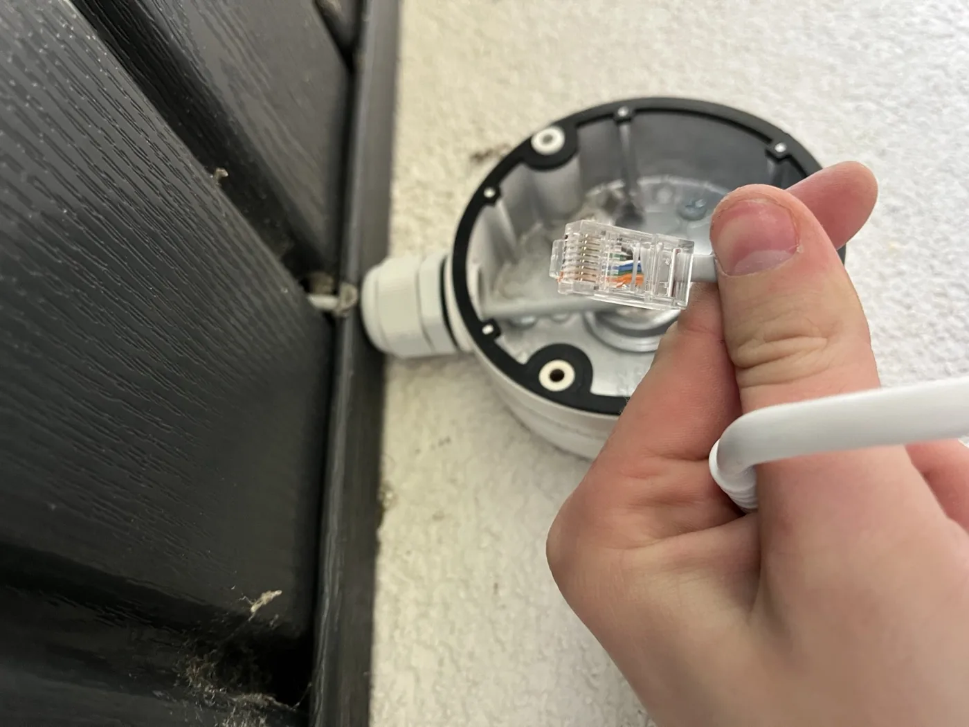 Instalacja kabla sieciowego z wtykiem RJ45 w puszce montażowej kamery monitoringu na elewacji budynku