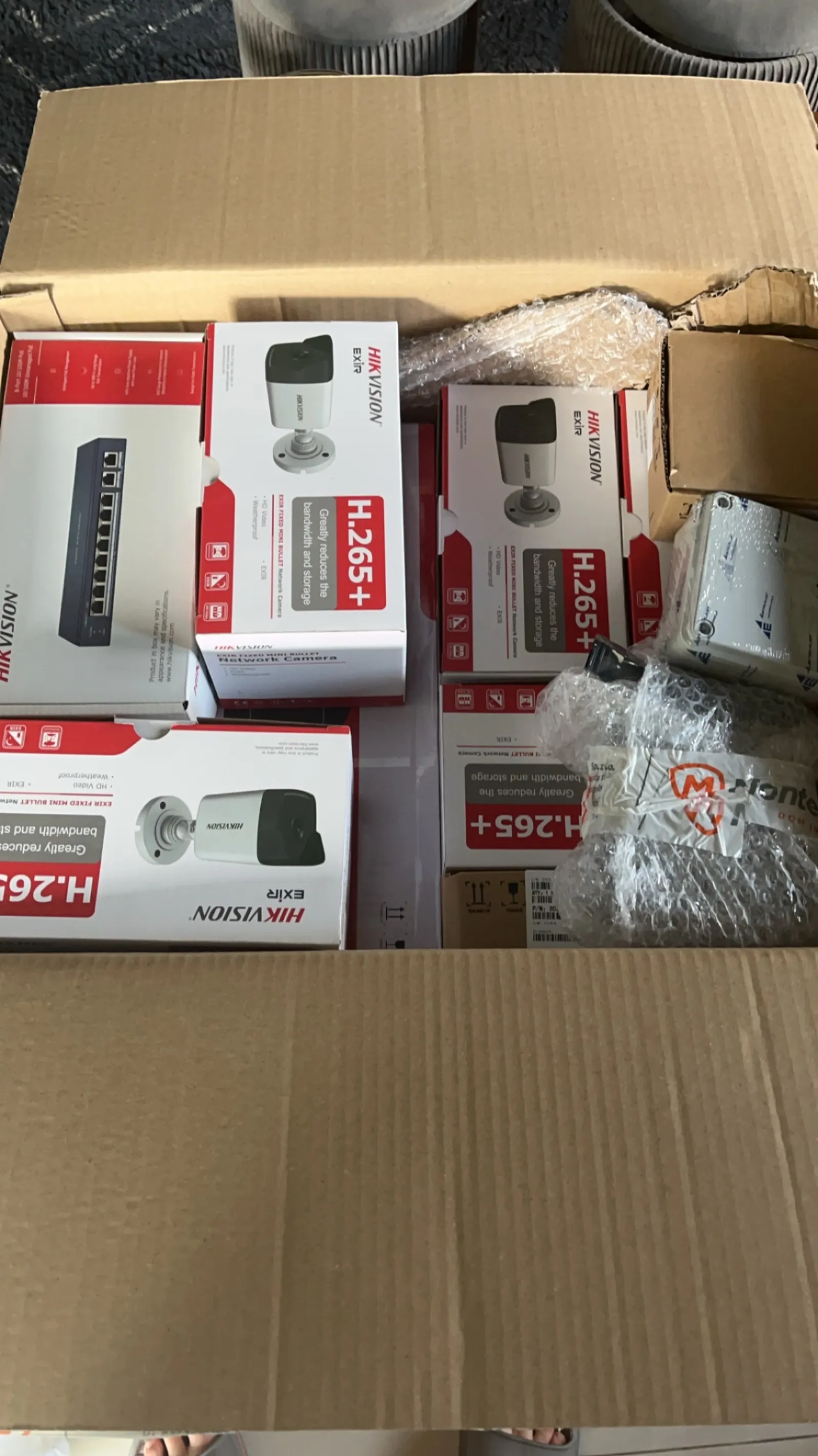Otwarty karton z markowym osprzętem monitoringu firmy Hikvision używanym do instalacji.